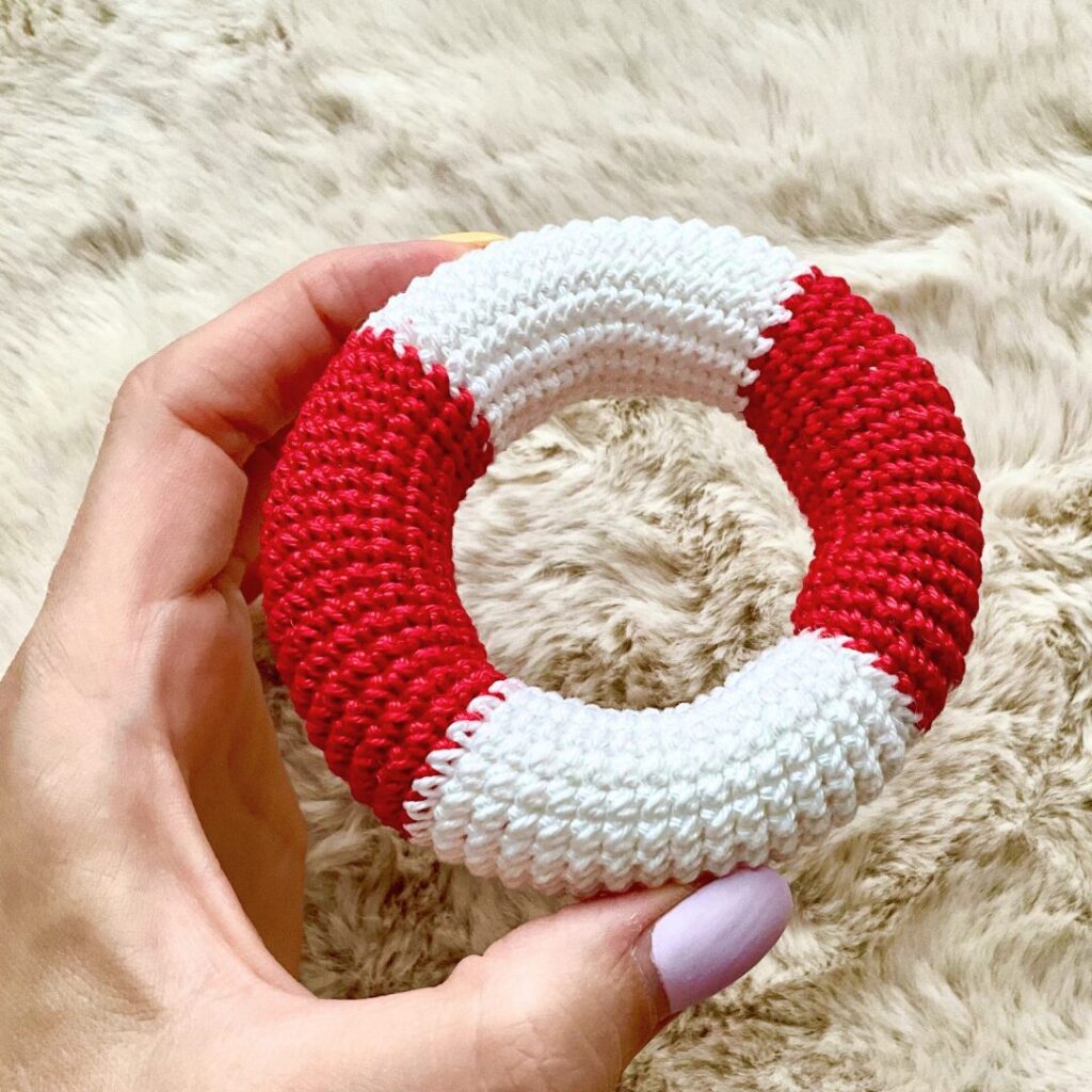 Hand holding Crochet Life Buoy in red and white colors in progress