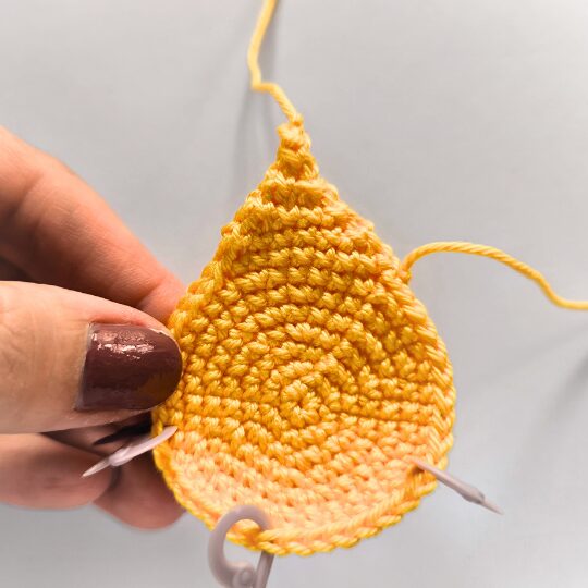 Working on a crochet star, where is ready the first spike. Body is in yello color and there are 3 markers in violet color